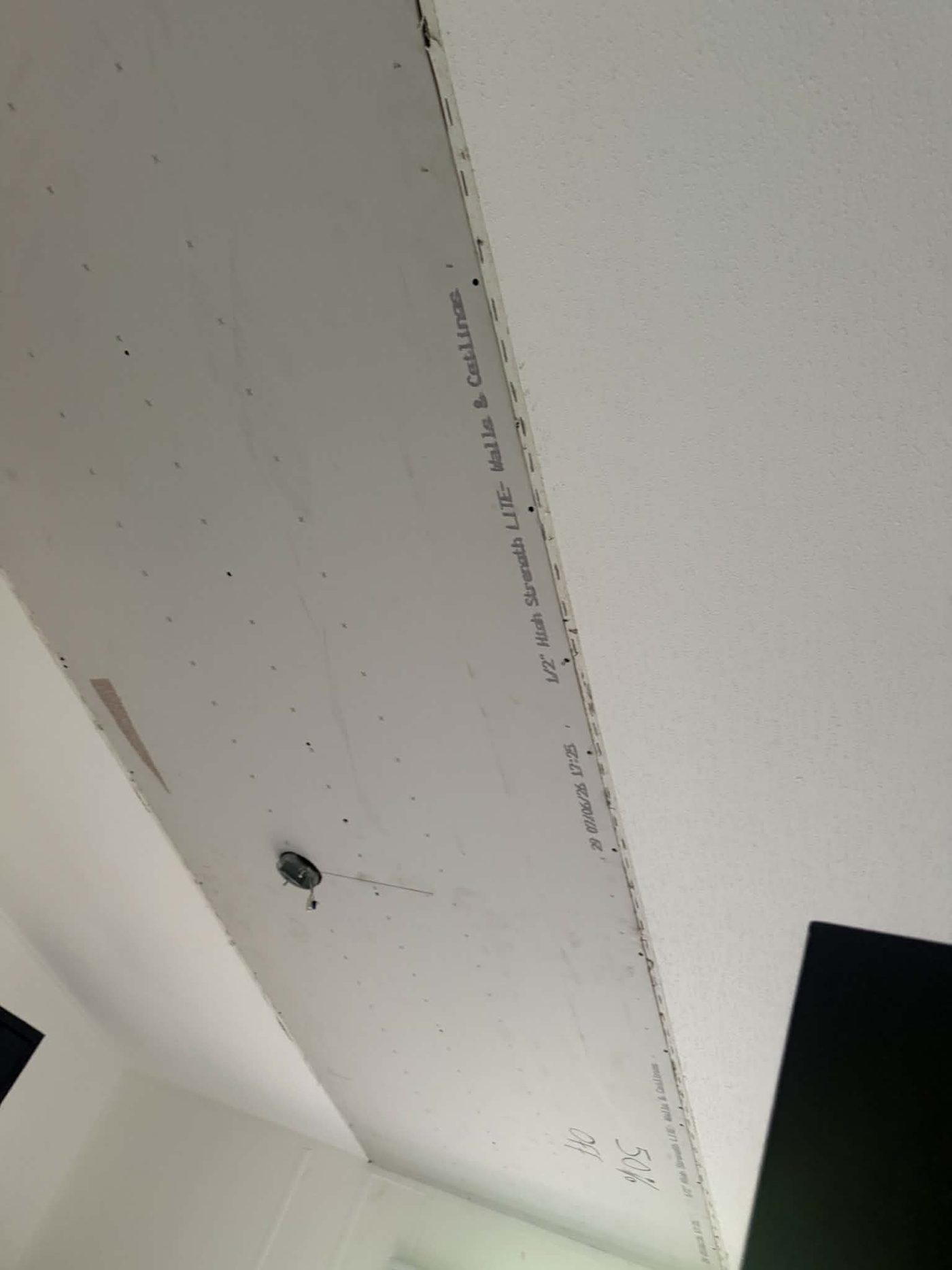 New drywall hung on a ceiling with fasteners visible, ready for taping and finishing
